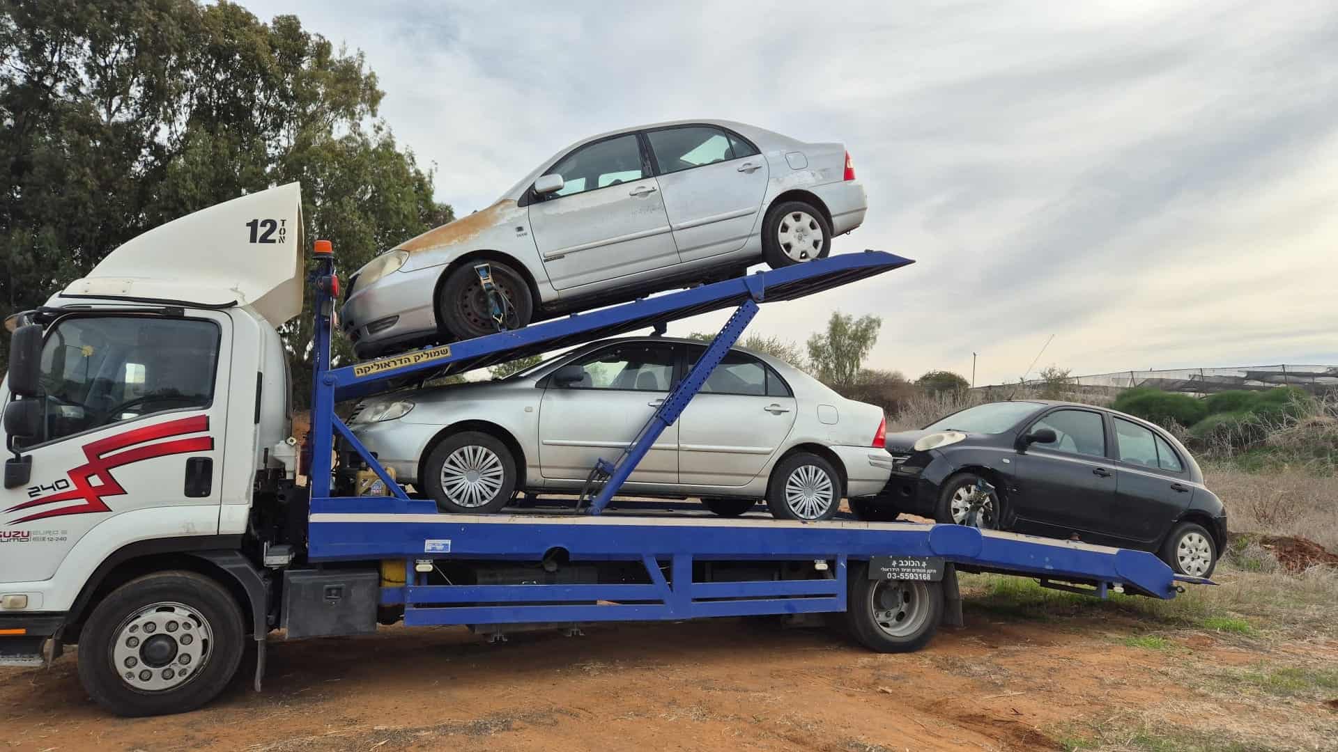 משאית ההובלה של eco-car מעמיסה רכבים ישנים בדרך למגרש הפירוק